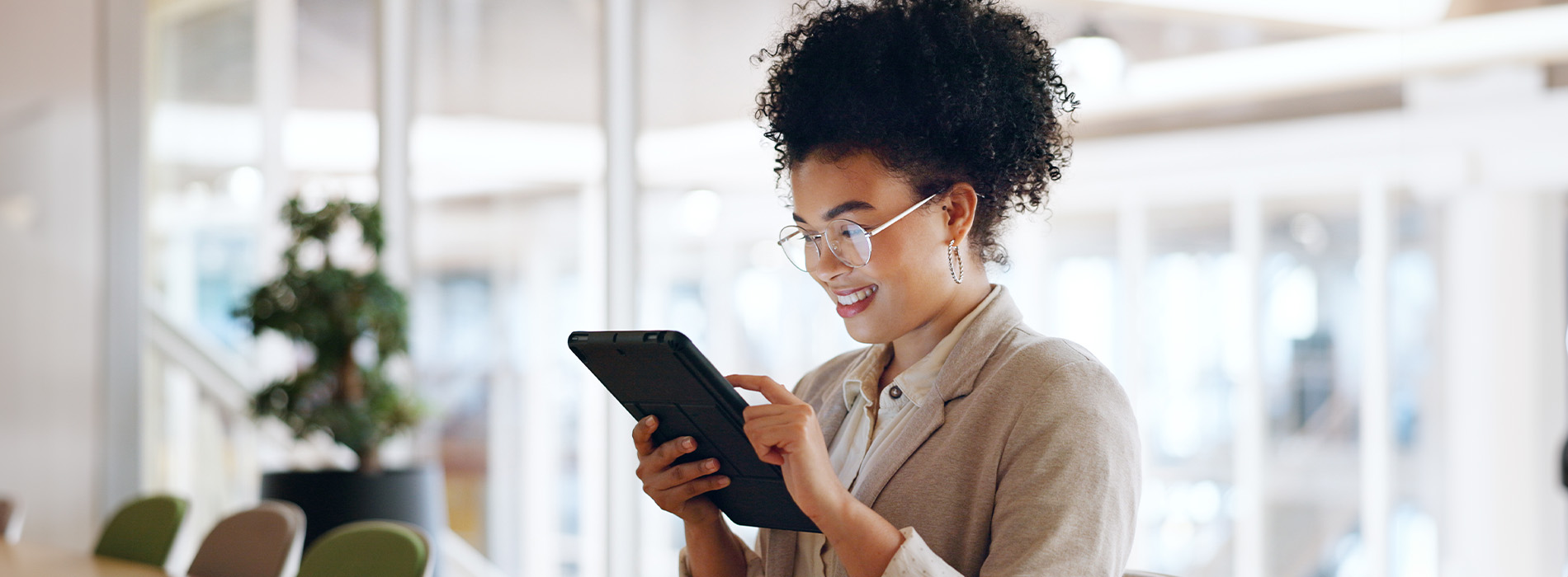 Woman standing at a desk, looking at her phone with a smile on her face.