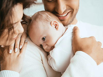 A family holding a baby in a warm embrace with a loving expression.