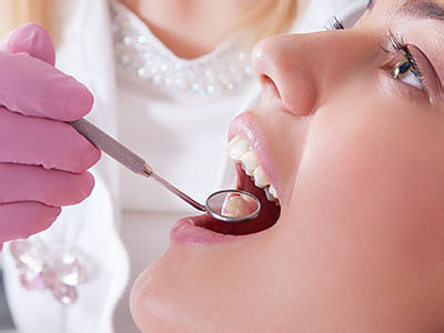 A woman receiving dental treatment, with a dental professional performing the procedure using specialized tools.