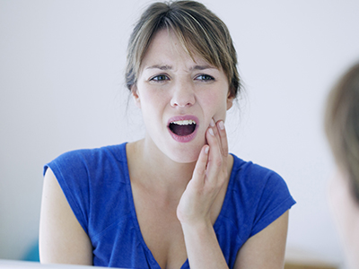 A woman with her hand on her chin, appearing surprised or concerned, looking at another person who seems to be speaking to her.