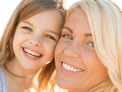 The image features a woman with a child standing close to her, both smiling at the camera.