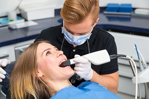 A dental hygienist performing a teeth cleaning procedure on a patient in a dental office setting.