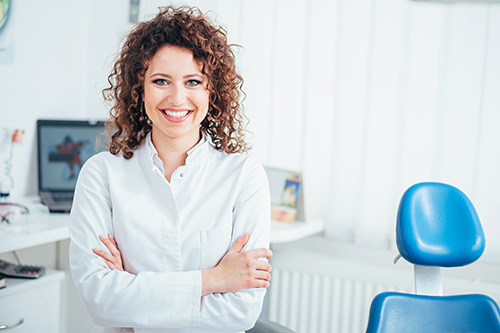 The image features a woman standing confidently in an office setting, smiling at the camera, with her arms crossed.