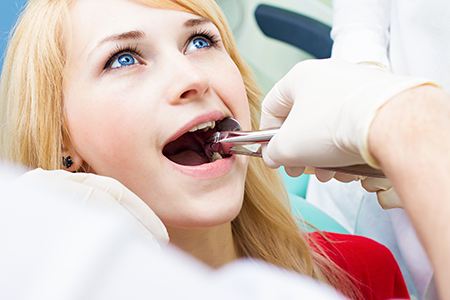 A young woman receiving dental care with a dentist assisting her.