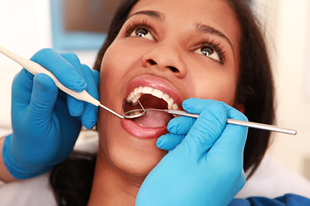 A woman receiving dental care with a dentist adjusting her braces.
