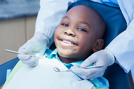 A young boy sitting in a dentist s chair with a smiling expression while receiving dental treatment.