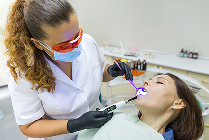 A dentist performing oral care on a patient in a dental office setting.