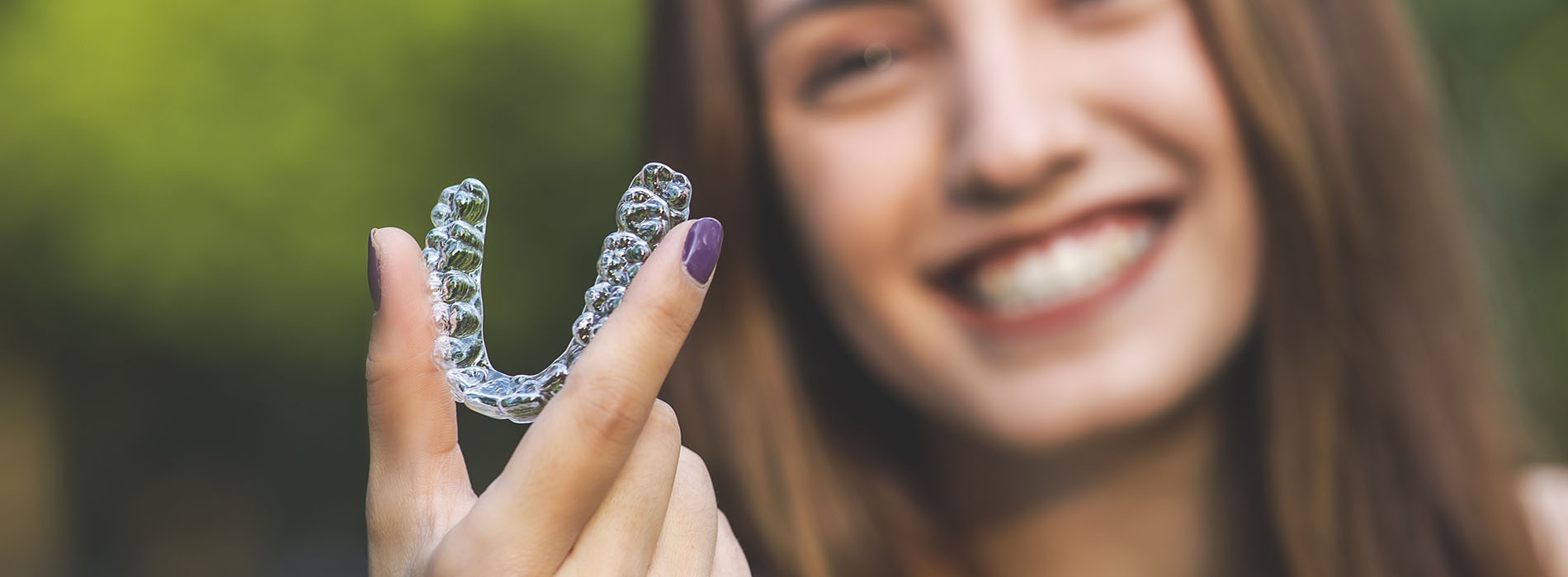 The image features a woman holding up a transparent object with the letters  S  and  C  etched into it, set against an out-of-focus background.